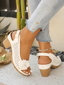 Detailed view of white high heel sandals with flower applique and laser-cut pattern