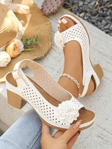 Close-up of white block heel sandal featuring a 3D flower and laser-cut design.