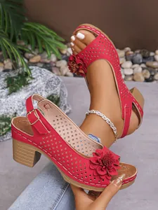 Detailed macro view of red floral wedge sandals featuring laser-cut hole patterns and straps
