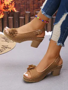 Detail of tan wedge sandals with flower accents and laser-cut design