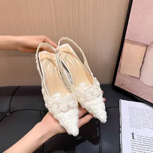 Detail showing the intricate rose lace pattern on white mesh pointed-toe slingback heels.