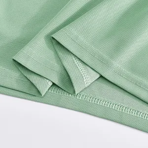 Macro view showing the high-quality overlock stitching on a light green mesh polo shirt hem.