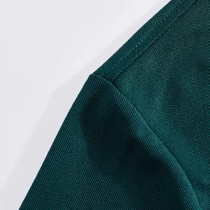 Macro detail shot of dark green breathable mesh fabric on a men's quick-dry golf Polo shirt.