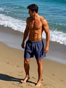 Male model wearing navy blue linen drawstring beach shorts on a sunny sandy shore
