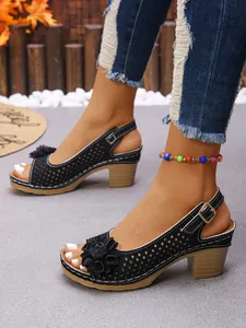Side view detail of black chunky heel sandals with elegant flower ornament and buckle