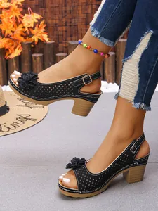 Close-up detail of black high-heeled sandals featuring floral accents and adjustable buckle straps