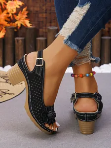 Close-up detail of black high heel sandals with laser-cut pattern and flower decor