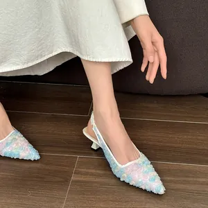 Detail view of French-style lace slingback heels with floral texture on wood floor