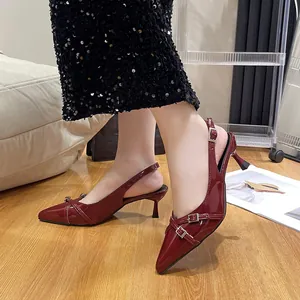 Eleganti tacchi a gattino bordeaux a punta con cinturini con fibbia in argento indossati al piede