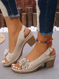 Close-up of elegant beige chunky heel sandals with 3D flower and perforated details
