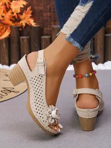 Detailed view of beige women's chunky heel sandals with decorative flower and hollow-out design.