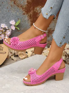 Close-up detail of vibrant pink high-heeled sandals with flower and cutout pattern