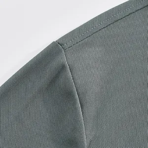Close-up of durable shoulder stitching and breathable mesh fabric on a grey Polo shirt.