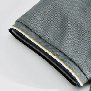 Detailed macro view of a gray polo shirt sleeve with navy and yellow striped ribbed cuffs