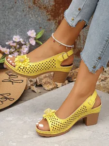 Detail of yellow high-heeled sandals with flower embellishments and cutout design