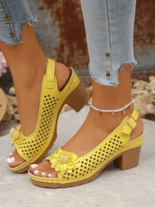 Close-up view of yellow hollow-out high heel sandals with elegant flower decoration