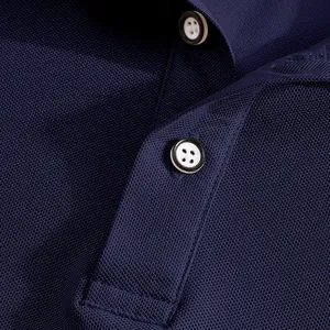 Macro view of navy blue mesh polo shirt breathable fabric and white buttons detail