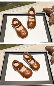 Detalle de zapatos Mary Jane marrones para niñas con una bonita decoración de flores naranja