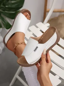 Close-up of white platform wedge sandals featuring open-toe design and leather strap