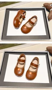Detalle de los zapatos Mary Jane de cuero marrón para niñas con lindo adorno floral