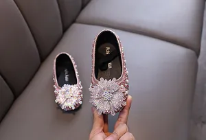 Detailed view of pink princess shoes featuring a large sparkling rhinestone flower ornament.