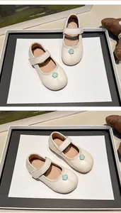 Primer plano de zapatos Mary Jane crema para niña con pequeña flor azul y suela blanda