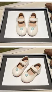 Vista detallada de los zapatos Mary Jane crema para niñas con un adorno de flor azul