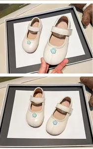 Primer plano de merceditas color crema para niñas con una bonita flor azul decorativa