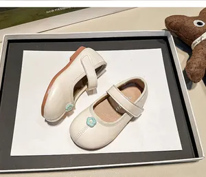 Detalle de los zapatos de cuero crema para niñas con bordado de flor azul