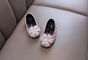 Detailansicht von funkelnden Mädchenschuhen in Rosa mit großen Strassblumen-Akzenten.