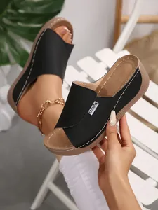 Stylish black wedge platform slippers featuring wide straps and a fashion label detail