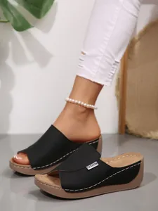 Close-up view of black platform wedge sandals with stylish peep-toe design and wide straps