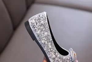 Nahaufnahme silberner Mädchen Prinzessinnenschuhe mit funkelnden Strasssteinen und Perlen.