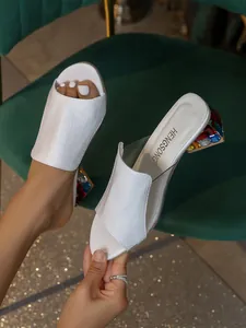 Detaillierte Nahaufnahme weißer Sandalen mit Kroko-Prägung und bunten Strass-Absätzen