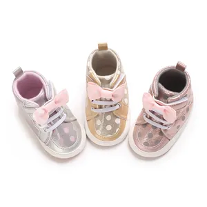 Nahaufnahme von gepunkteten Babyschuhen mit rosa Schleifen in Silber, Gold und Rosé-Metallic.