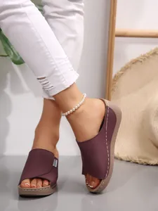 Close-up of women's purple wedge slides with platform sole and white stitching