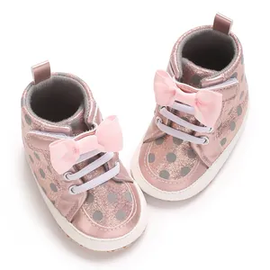 Vue détaillée de chaussures pour bébé roses avec pois et un joli nœud décoratif rose