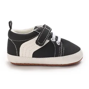 Close-up side view of black and white baby sneakers featuring Velcro strap and soft sole