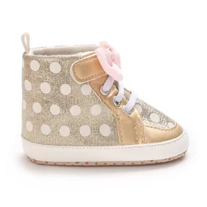 Detailansicht von goldenen gepunkteten Babyschuhen mit weicher Sohle und Schleife