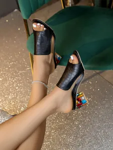 Detailansicht von schwarzen Sandalen mit Kroko-Prägung und bunten Kristall-Blockabsätzen.