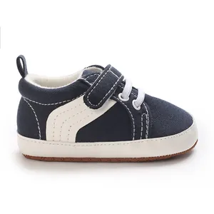 Side detail of infant navy canvas sneakers with white soft sole and hook-and-loop strap