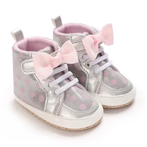 Détail de chaussures de marche pour bébé argentées avec pois roses et nœuds décoratifs