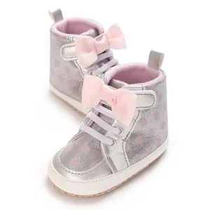 Détail de chaussures de marche pour bébé argentées avec pois roses et nœud mignon