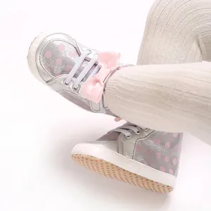 Détail de chaussures argentées pour bébé avec pois roses et un nœud décoratif élégant