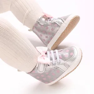 Gros plan de chaussures de marche pour bébé argentées avec pois roses et semelles