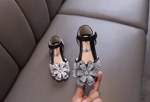 Detail view of girls' black princess shoes featuring a large sparkly rhinestone flower