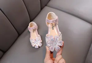 Close-up of pink girls' princess shoes featuring a large rhinestone flower detail.