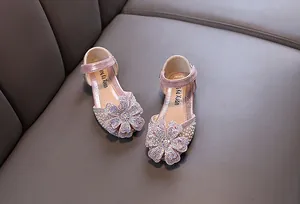 Detailed view of pink glittery girl's shoes with large rhinestone flower and pearls.