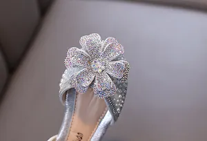 Macro view of the sparkling rhinestone flower and pearl decoration on silver princess shoe