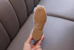 Macro view showing the durable rubber anti-slip outsole of a girl's silver rhinestone flat.